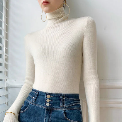 Model wearing the fine ribbed roll neck jumper in ivory, tucked into high-waisted blue denim with large hoop earrings 4