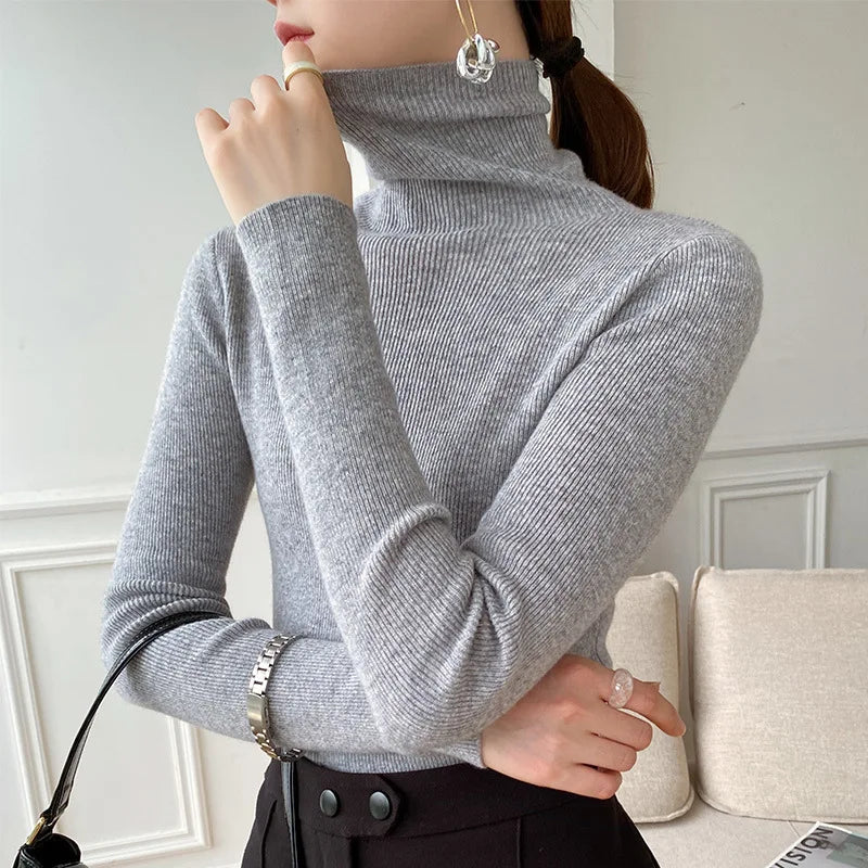 Model wearing the ribbed roll neck jumper in light grey with a silver watch and black trousers, seen from the side 7