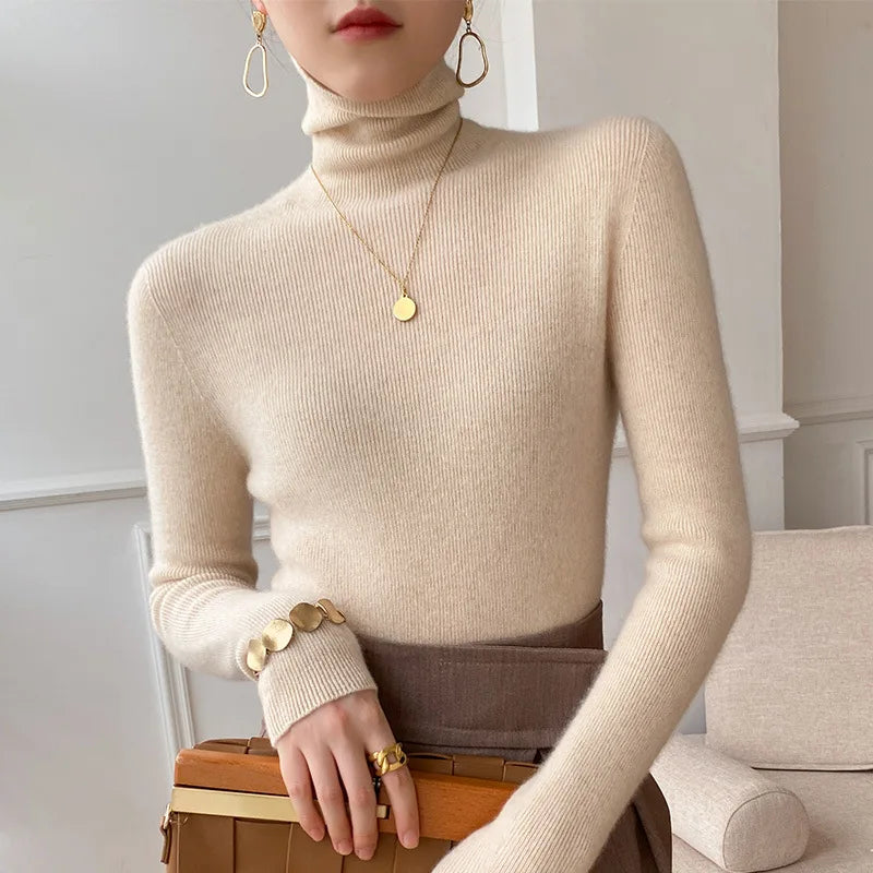 Model wearing the ribbed roll neck jumper in cream with a gold pendant, brown skirt and tan handbag 1
