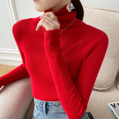 Model wearing the snug ribbed roll neck jumper in bright red, hand raised to her chin, with light blue jeans 5