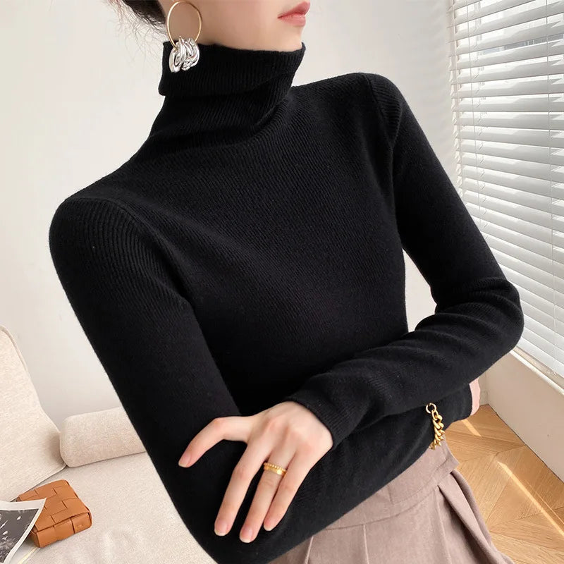 Model wearing the slim roll neck jumper in black with a taupe pleated skirt and gold ring, arms crossed 8