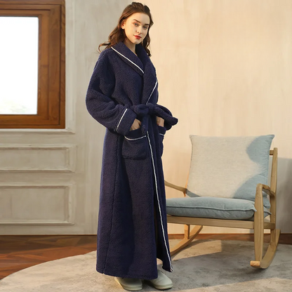 Side view of a navy fleece robe with white piping, hands in pockets, beside a rocking chair 10