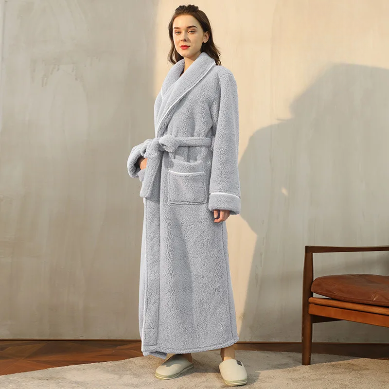Model in a pale grey fleece robe with a knotted belt, standing in three-quarter view by a leather chair 3
