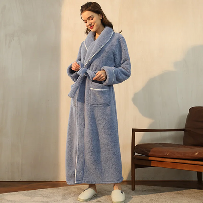 Model looking down while tying the belt of a dusty blue fleece robe with white piping 4