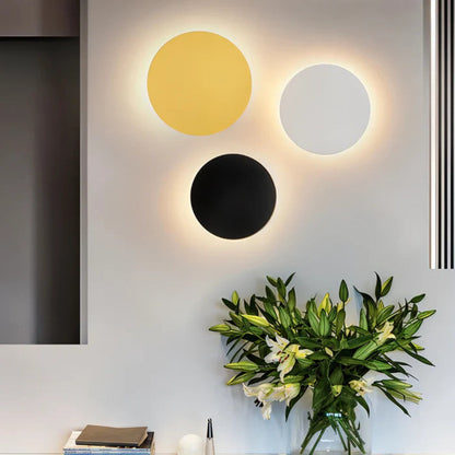 Gold, white and black discs hung together on a wall above a vase of lilies 4