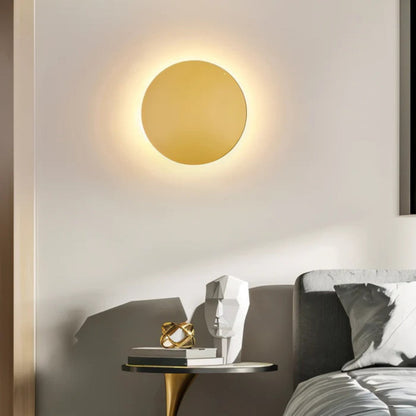 Gold disc lit above a bedside table with books and ornaments, beside a grey headboard 6