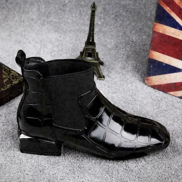 Side view of a black patent croc-effect Chelsea-style ankle boot with elastic gusset, low block heel and pull tab, on grey carpet. 2