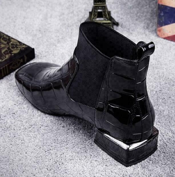 Rear three-quarter view of the black croc-effect ankle boot, showing the pull tab, textured heel counter and chunky block heel with metallic trim. 3