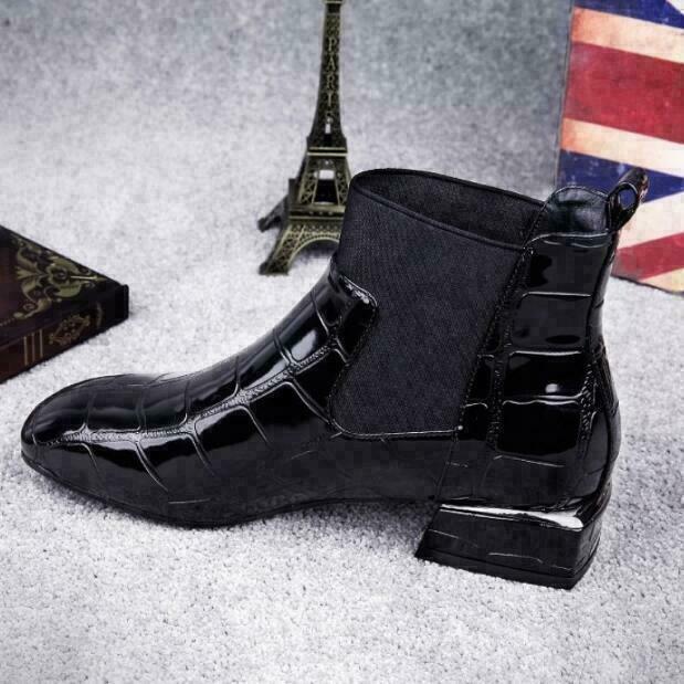 Outer side view of the black patent croc-effect ankle boot, with stretchy side panel, square block heel and a flag-print backdrop. 6