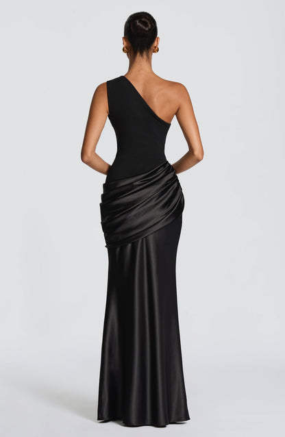 Back view of a black one-shoulder gown on a model, showing the asymmetric strap, fitted bodice and draped satin hip panel. 21
