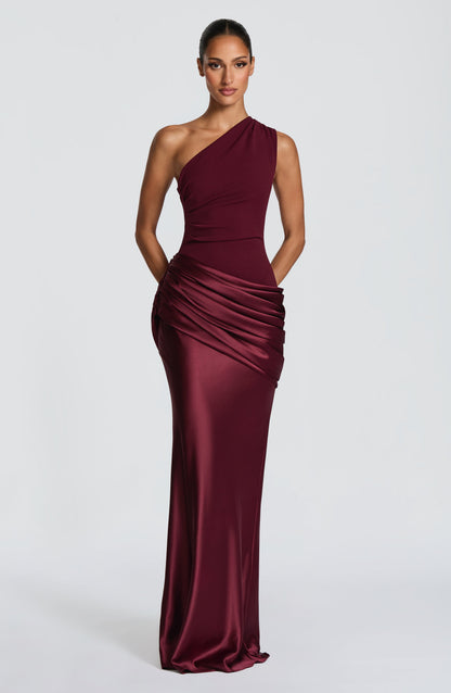 Straight-on front view of the burgundy dress with hands tucked behind, showing the drape across the hip. 19