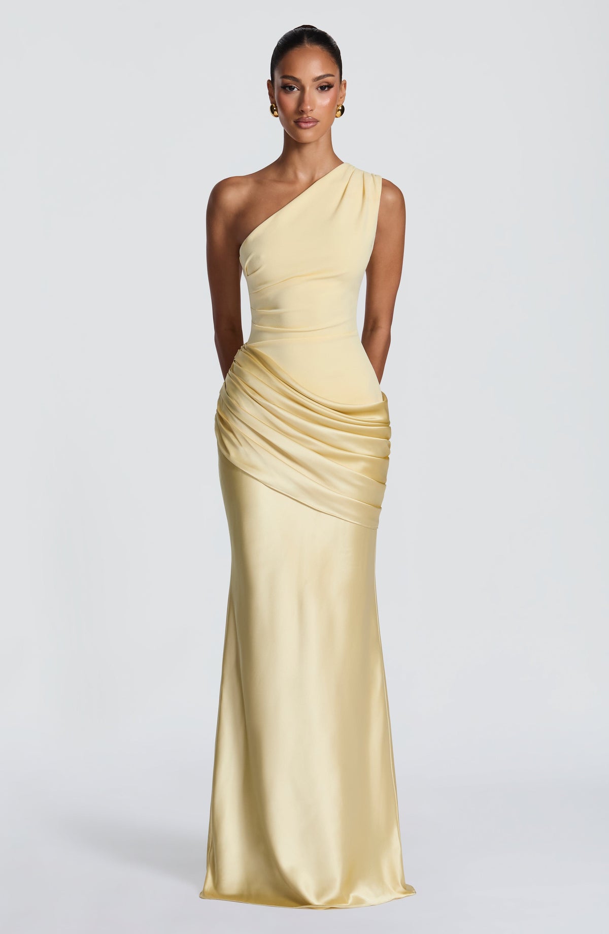 Front view of the pale yellow one-shoulder maxi dress on a model, with a fitted bodice and draped satin waist. 26