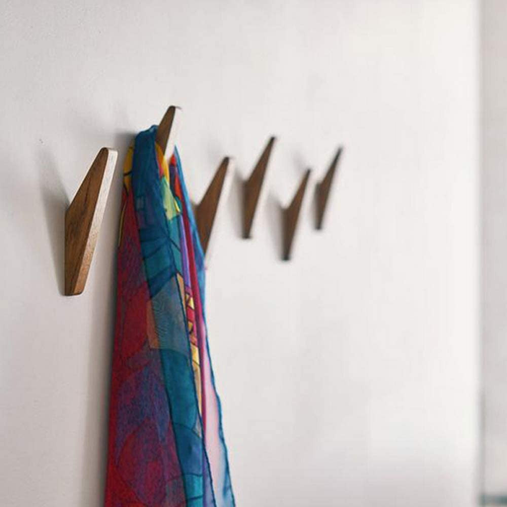 Row of darker wooden hooks on a white wall, with a colourful patterned scarf in red, blue and yellow hanging from one. 3