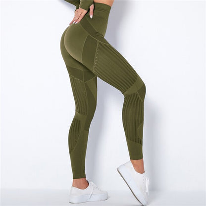 Olive green high-waisted leggings seen from the side, with ribbed striped panels and a model's hand on her hip 5