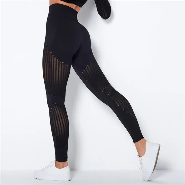 Rear view of black high-waisted leggings with sheer striped panels on thighs and calves, worn with white trainers 2