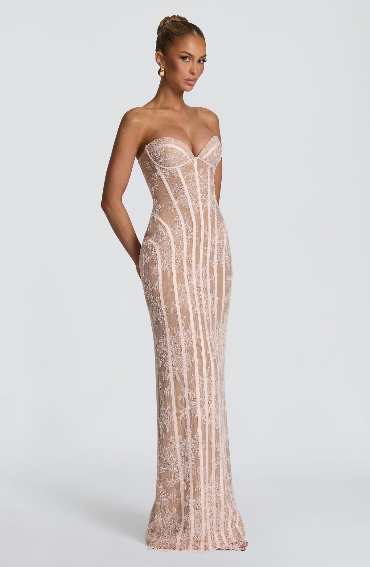 Angled side view of the blush pink strapless lace maxi dress with a model's arm bent behind her. 16