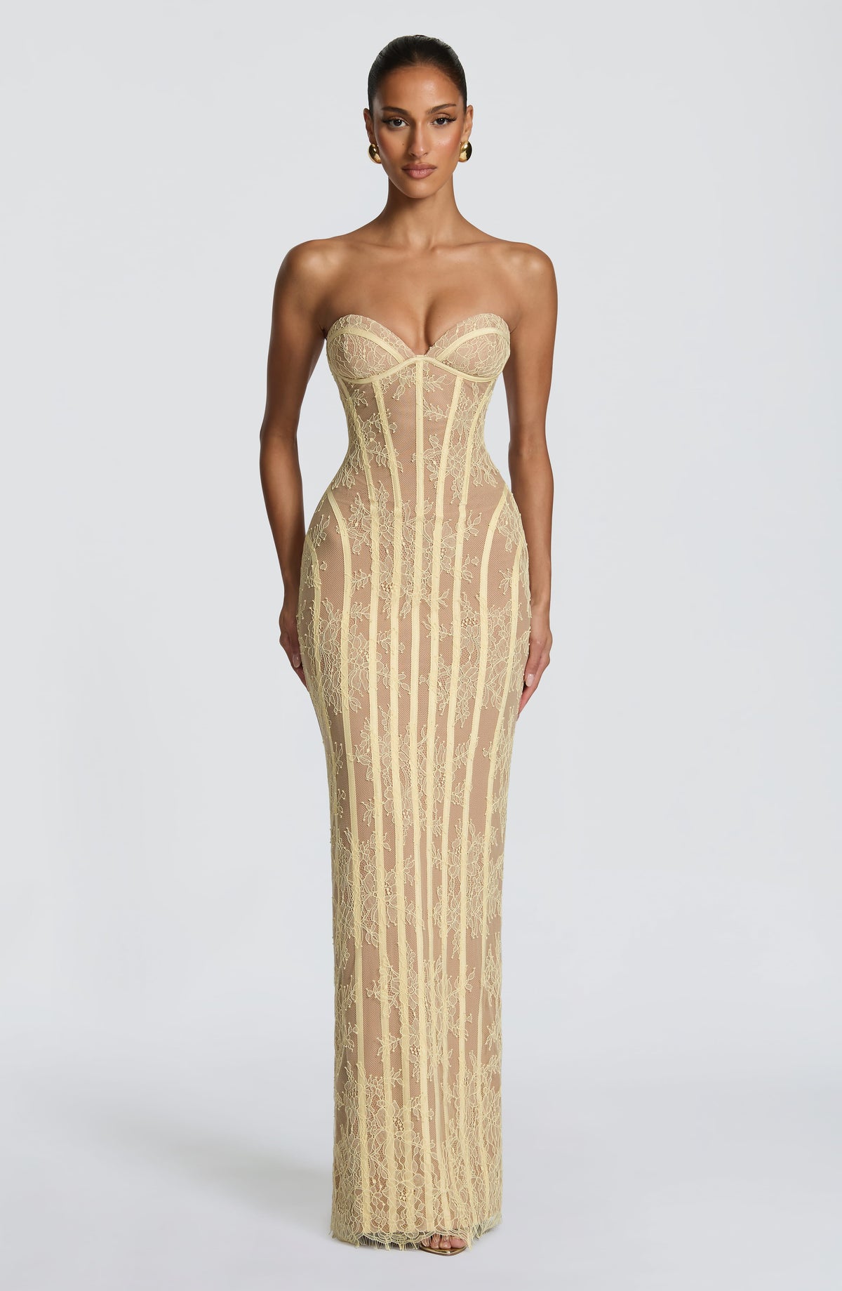 Model facing forward in a pale yellow strapless lace maxi dress with sweetheart neckline, vertical corset boning and a fitted column skirt. 21