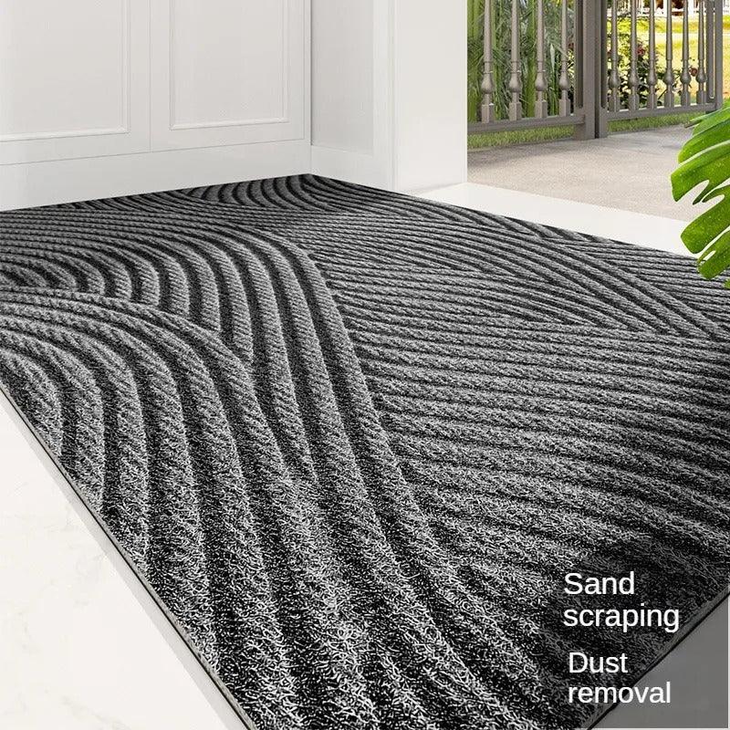 Close view of a grey mat with sweeping wave ridges at a front door, plant in foreground 7