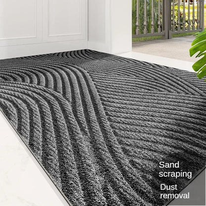 Close view of a grey mat with sweeping wave ridges at a front door, plant in foreground 7