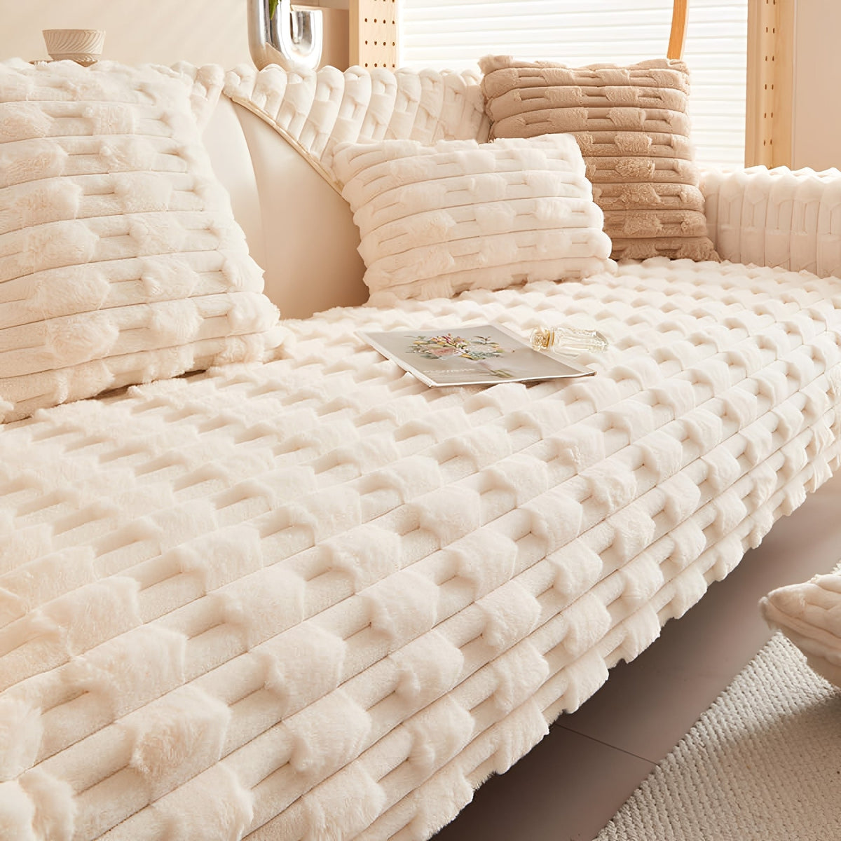 Cream plush cover fitted over a sofa seat and backrest, styled with cushions, a card and a small bottle. 8