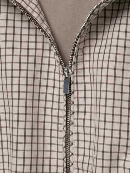 Close-up of the silver zip pull and metal teeth on the brown and cream checked fabric. 6