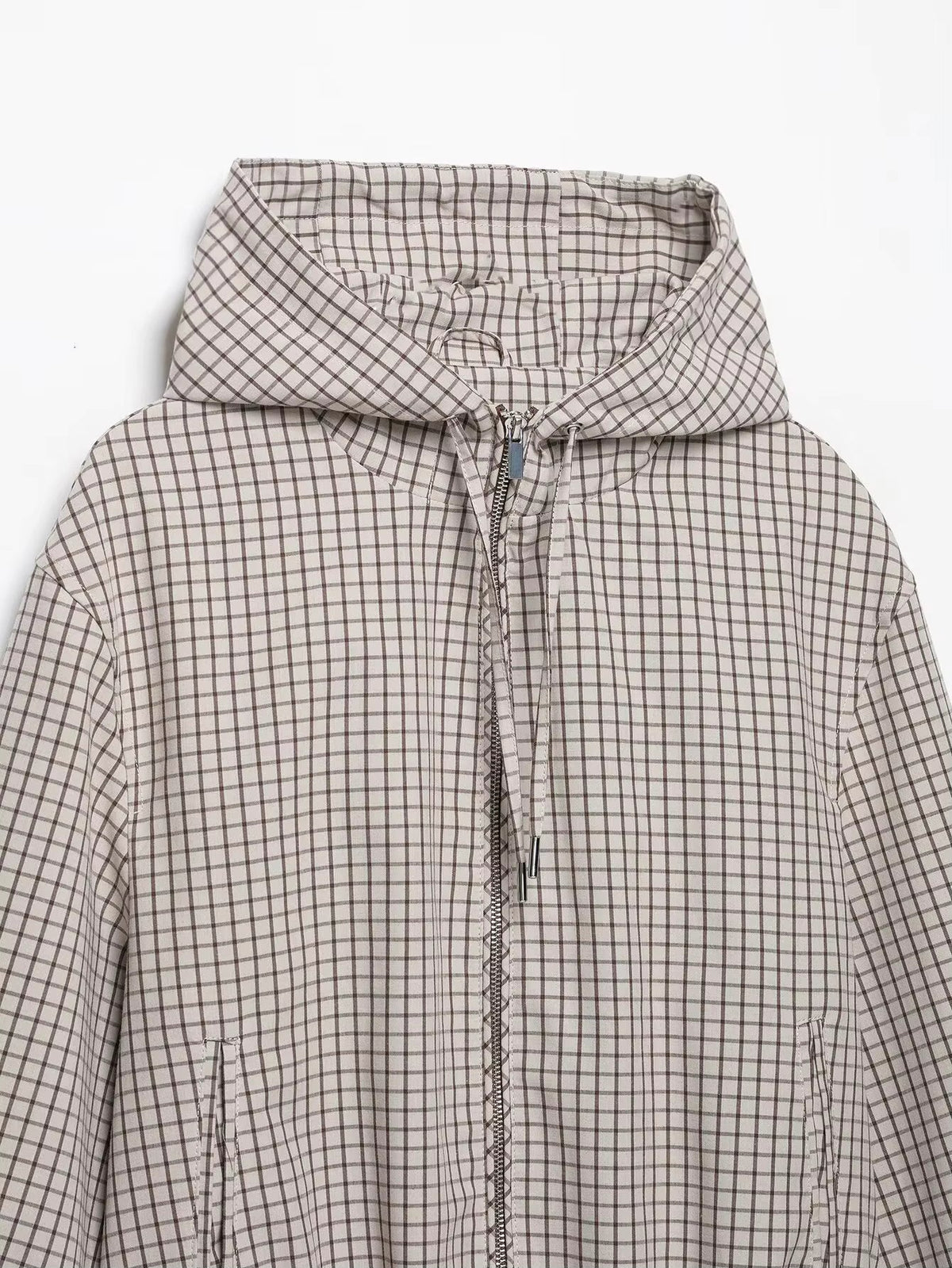 Flat lay of the jacket's upper half, showing the hood, zip, drawstring cords with metal tips and side pockets. 7