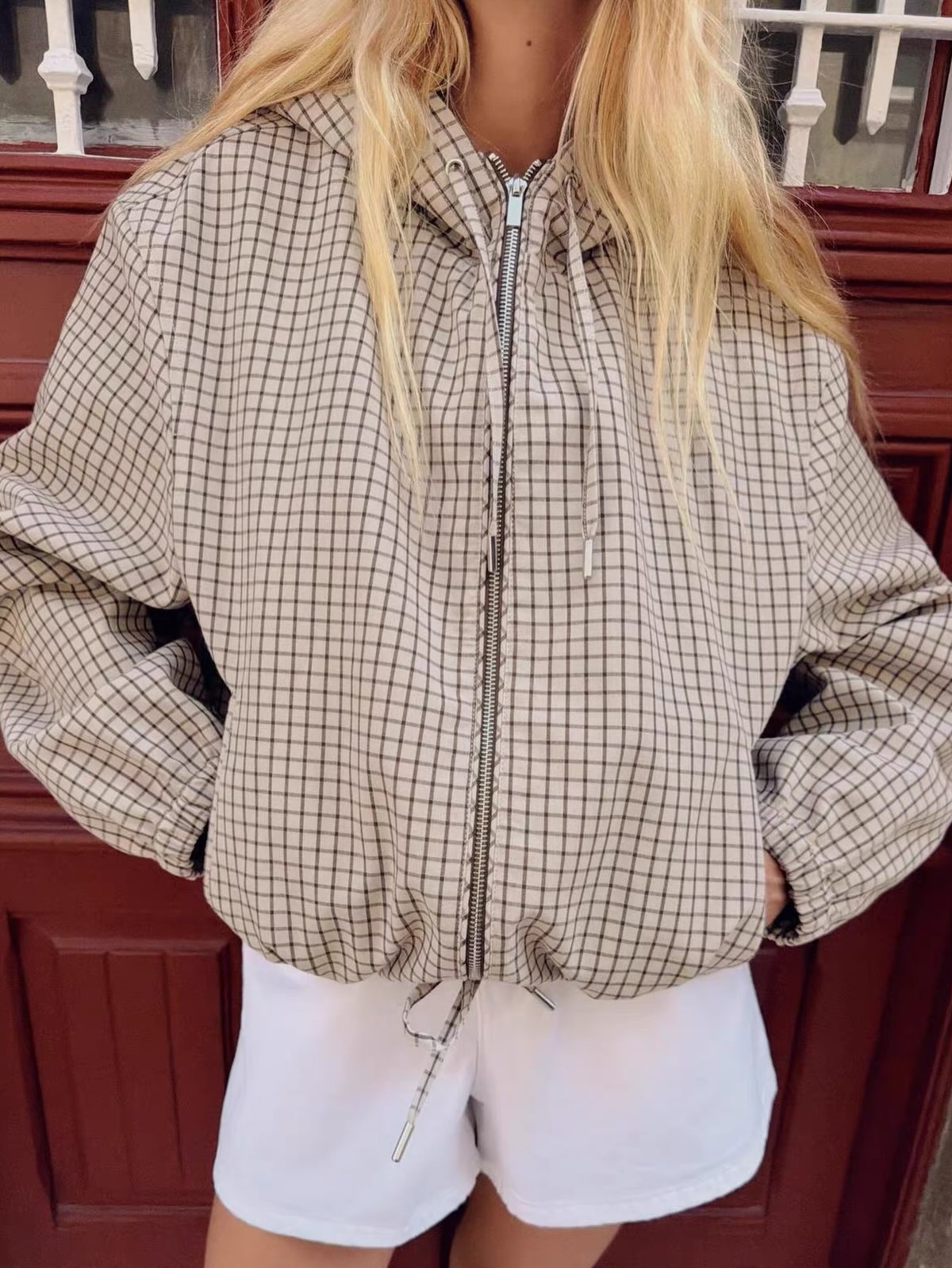 Close-up of the jacket's centre zip, drawstring hood cords and gathered drawstring hem on a model. 3