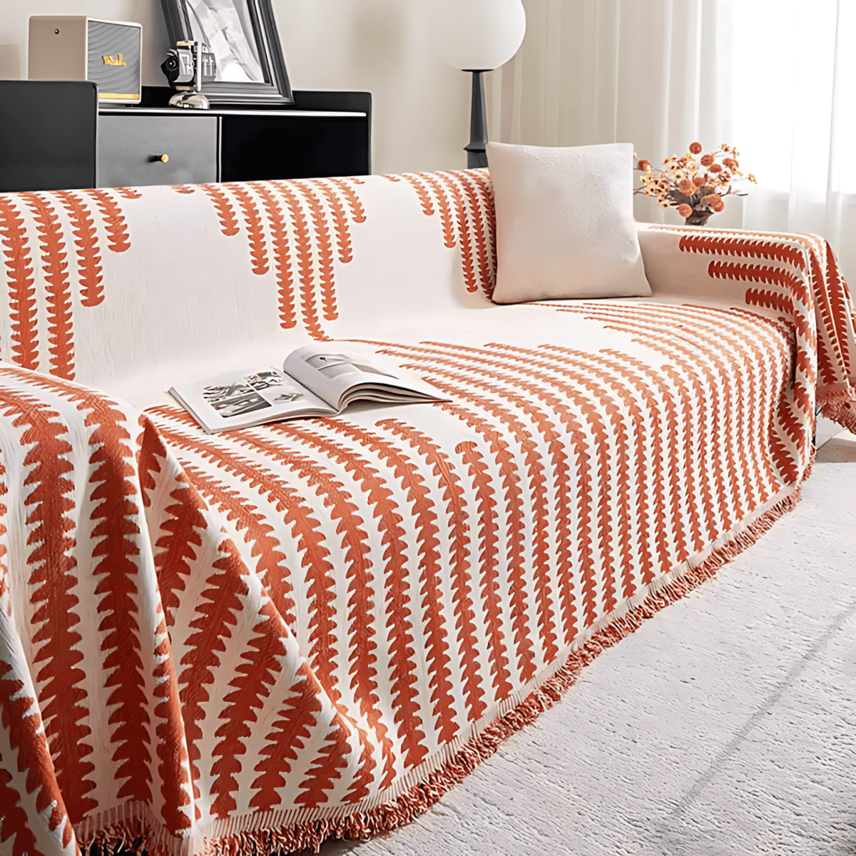 Burnt orange and cream colourway draped over a sofa, with a plain cushion, an open magazine and dried flowers beside it. 7