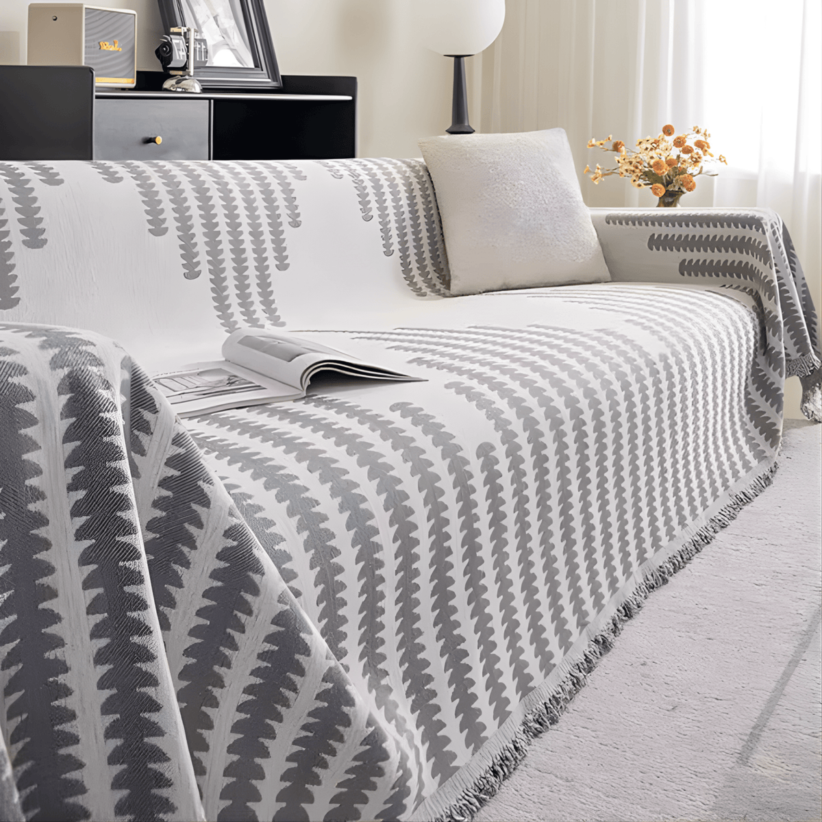 Grey and white colourway covering a sofa, with the fringed edge visible, an open magazine and a cream cushion. 8