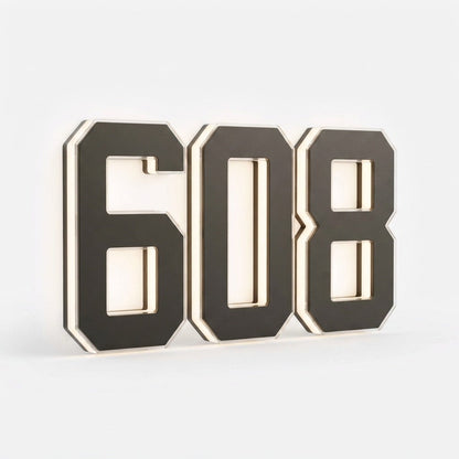 Three black digits spelling a house number on a plain white background, shown at an angle to reveal the layered edges and soft backlight. 19