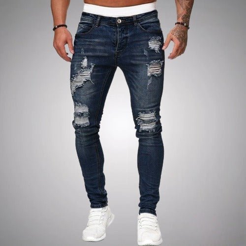 Front view of slim-fit ripped jeans in dark navy blue, worn with white trainers, showing distressed rips on thighs and knees. 4