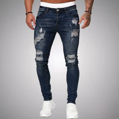 Front view of slim-fit ripped jeans in dark navy blue, worn with white trainers, showing distressed rips on thighs and knees. 4