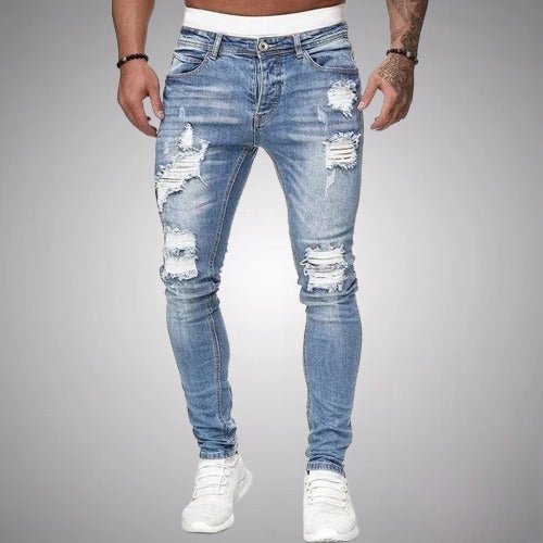 Front view of slim-fit ripped jeans in light blue wash, worn with white trainers, showing distressed rips across the thighs and knees. 2