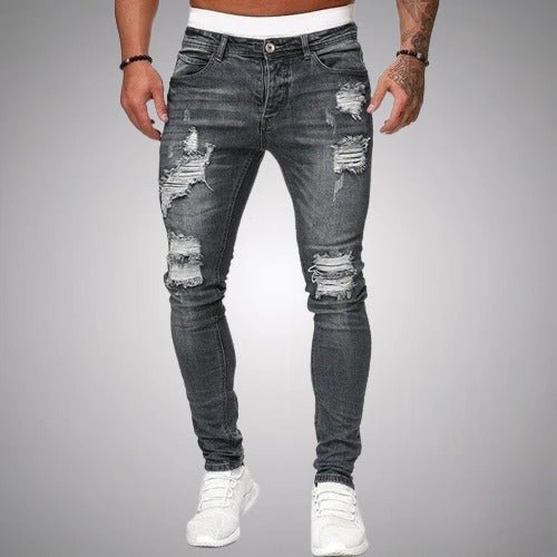Front view of slim-fit ripped jeans in a faded grey wash, worn with white trainers, showing frayed rips on thighs and knees. 5
