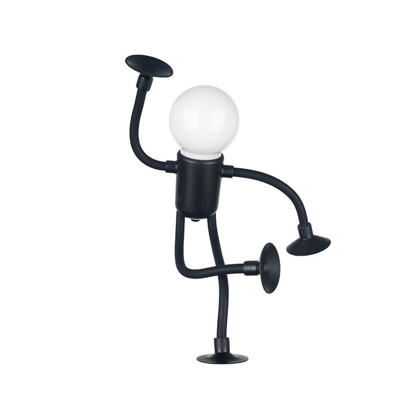 Black figure lamp balanced on one leg with a raised arm, frosted bulb head glowing and suction cups at each limb end. 15