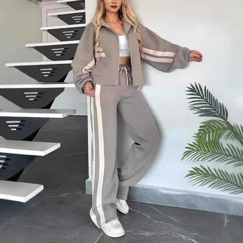 Model leaning against a wall in the grey set with cream stripes, wide sleeves and wide-leg trousers with drawstring waist. 6