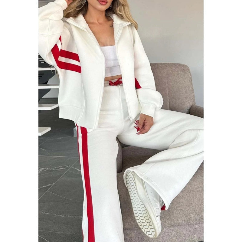 Close-up of the white and red set on a seated model, showing the jacket's high collar, front zip and wide-leg trousers. 2