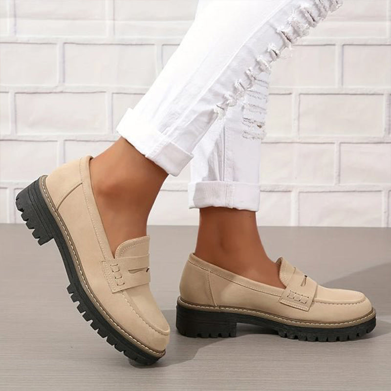 Beige loafers with stitched penny strap and thick black lugged sole, worn with ripped white jeans, shown in a walking pose. 3