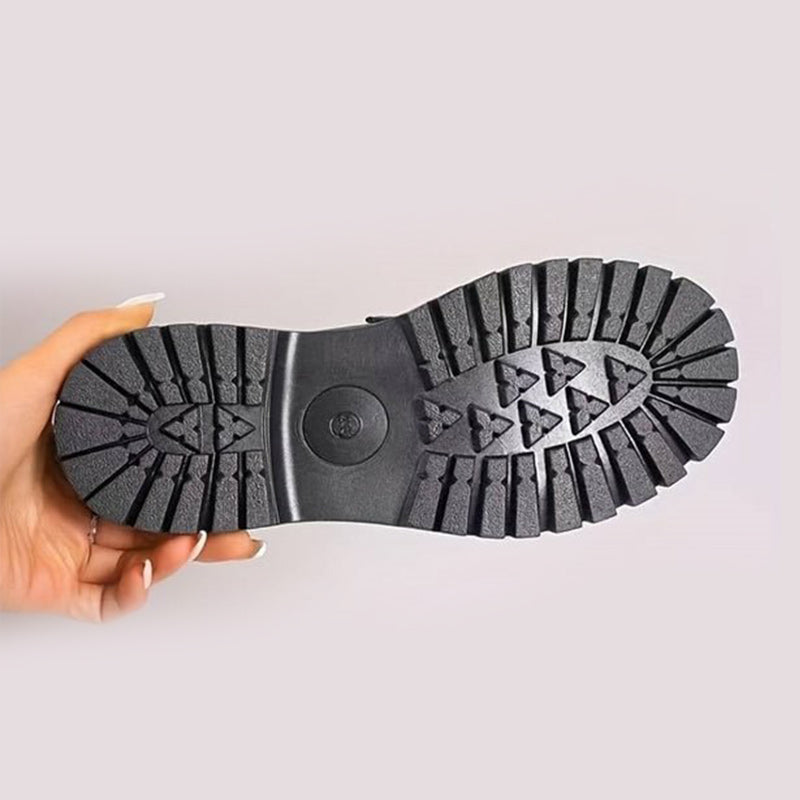 Underside of a loafer held in one hand, showing the deep black tread pattern on the chunky outsole. 10