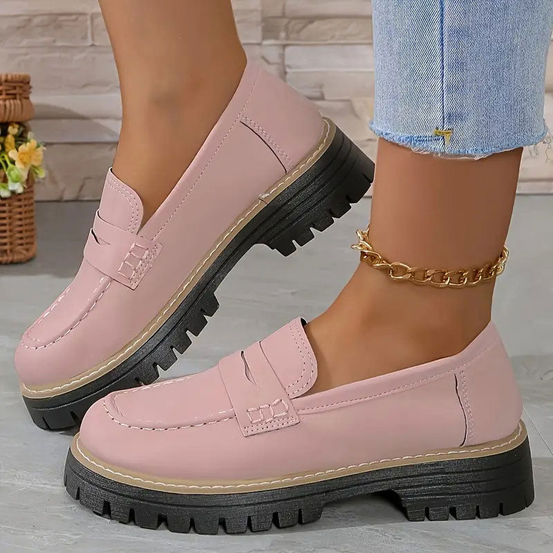 Pink smooth-finish loafers on a raised black platform sole, worn with a gold ankle chain and frayed light blue jeans. 11