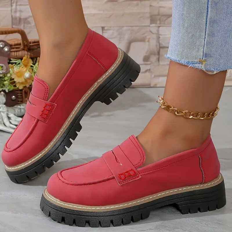 Red loafers with red stitching on the penny strap and a chunky black platform sole, worn with a gold anklet. 13