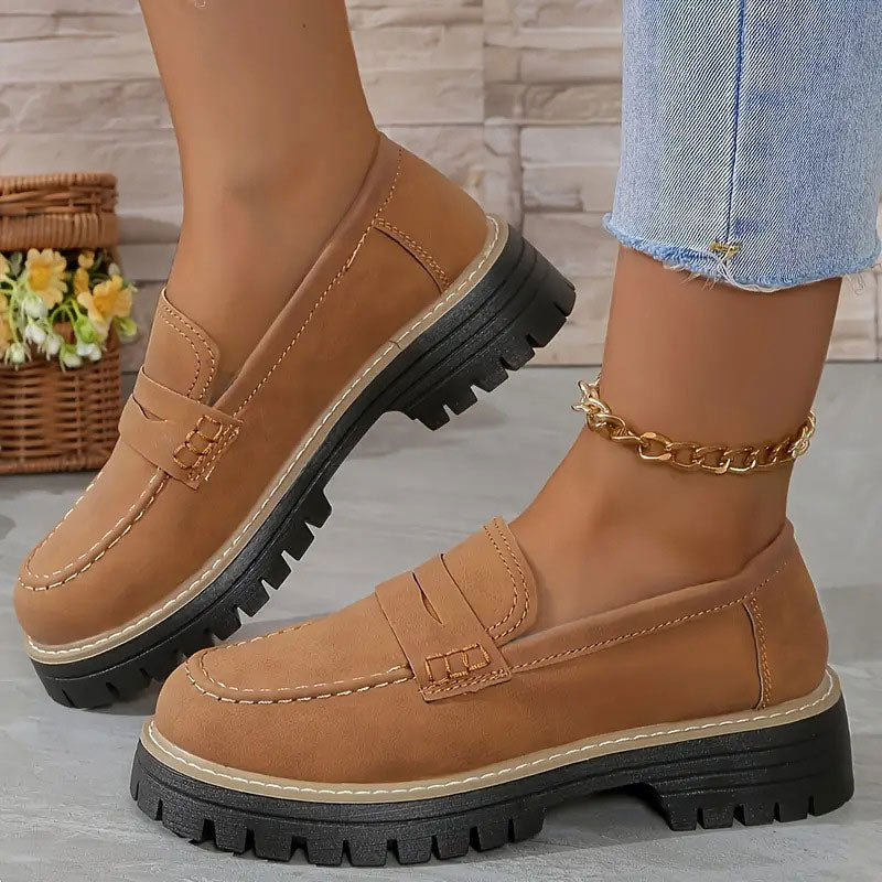 Light brown loafers with tan contrast stitching and a chunky black platform sole, worn with a gold chain anklet. 17