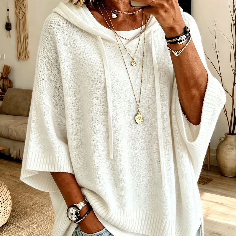 Close-up of a woman in the white hooded knit with long drawstrings, ribbed hem and cuffs, layered with gold necklaces. 8