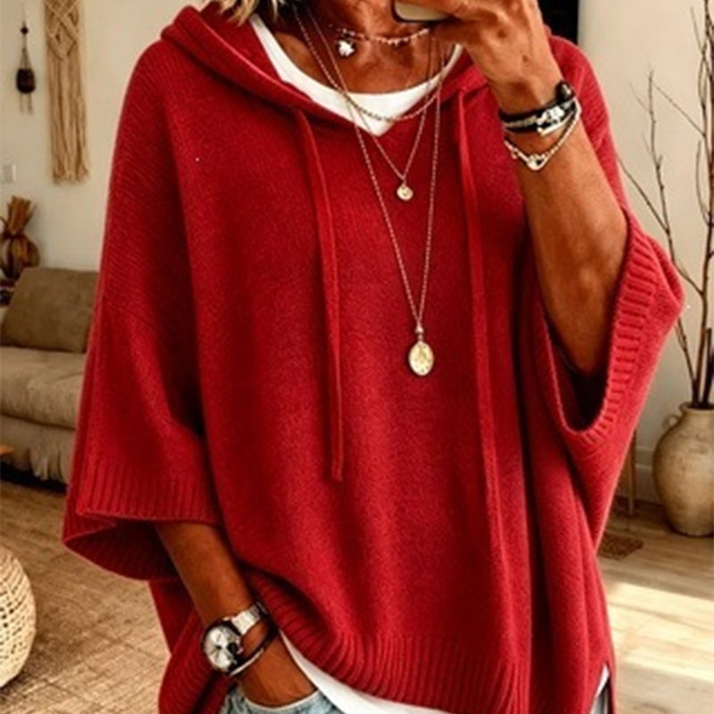 Close-up of the red hooded knit worn over a white top, with drawstrings, ribbed cuffs and layered necklaces. 13