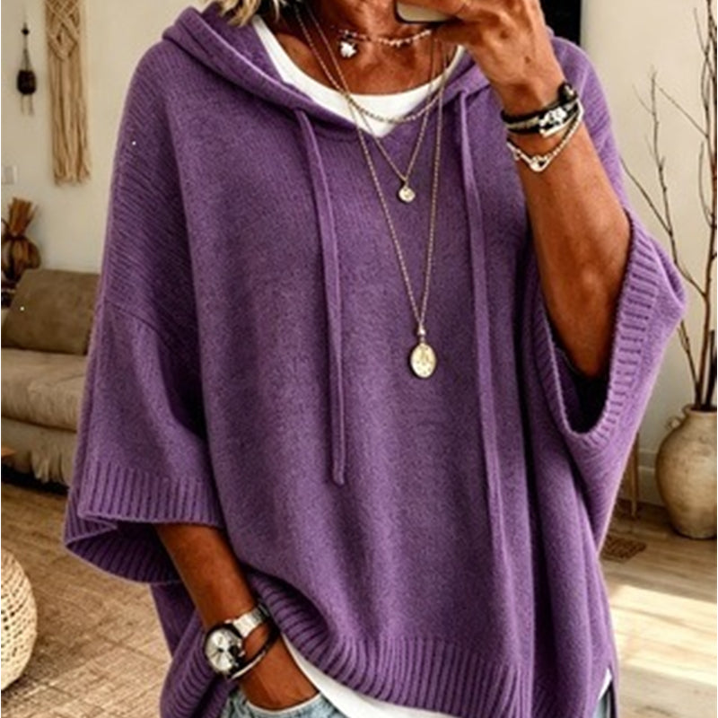 Close-up of the purple hooded knit worn over a white top, with drawstrings, ribbed cuffs and layered necklaces. 11