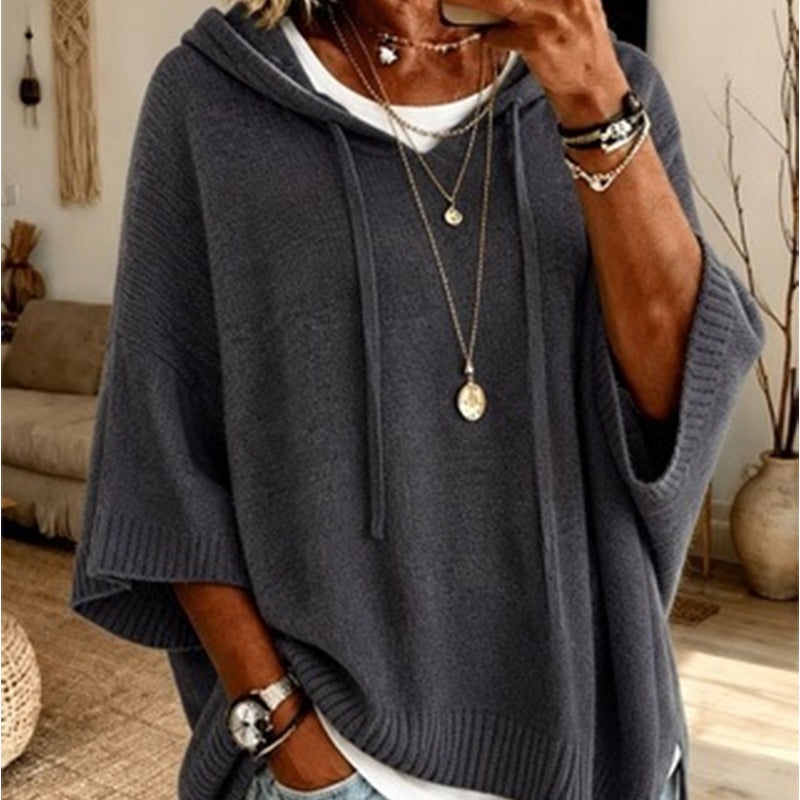 Close-up of the grey hooded knit worn over a white top, with drawstrings, ribbed cuffs and layered necklaces. 9