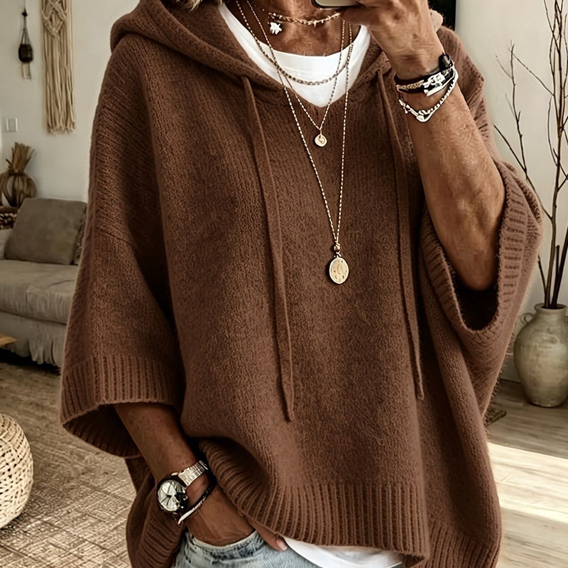 Close-up of the brown hooded knit worn over a white top, with drawstrings, ribbed cuffs and layered necklaces. 18