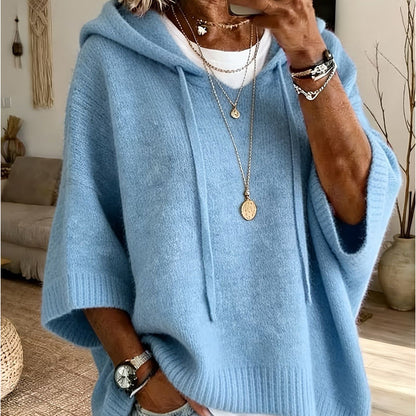 Close-up of the sky blue hooded knit worn over a white top, with drawstrings, ribbed cuffs and layered necklaces. 17