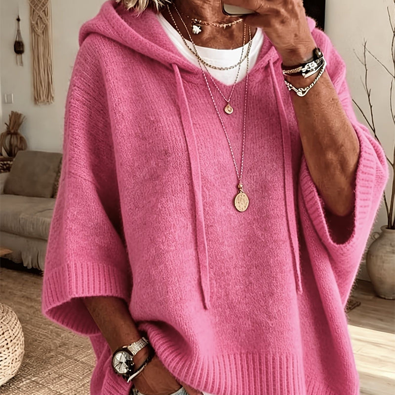 Close-up of the bright pink hooded knit worn over a white top, with drawstrings, ribbed cuffs and layered necklaces. 16