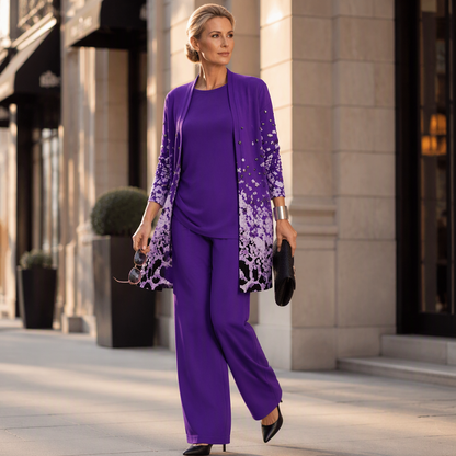 Woman walking along a city street in the purple set with black court shoes, holding sunglasses and a black clutch bag. 12